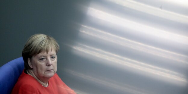 Angela Merkel hat etwas hellrotes an. Neben ihr helle Lichtstreifen