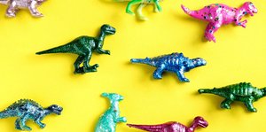 Bunte Dinosaurier aus Plastik vor gelbem Hintergrund