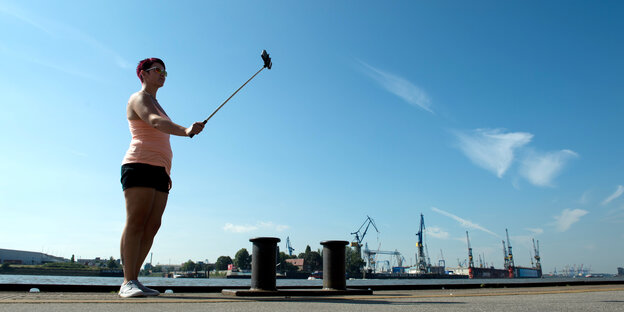 Eine Frau macht im Hamburger Hafen ein Selfie.