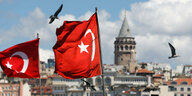 Zwei türkische Flaggen wehen im Wind. Im Hintergrund ist der Galataturm in Istanbul zu sehen.