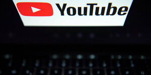 Ein Laptop von oben, auf dessen Bildschirm das Youtube-Loge: ein weißes nach rechts zeigendes Dreieck auf einem roten rechteckigen Hintergrund
