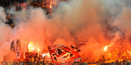 Die Fankurve der Dynamo Dresden Fans im orangen Licht zahlreicher gezündeter Bengalos
