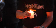 Ein Mann in einem schwarzen Tshirt mit der Aufschrift "Deutschland" hält bei einer rechten Kundgebung in Köthen eine Kerze