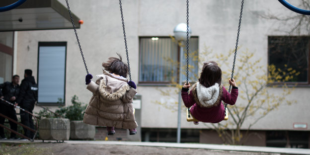 Zwei kleine Mädchen auf einer Schaukel.