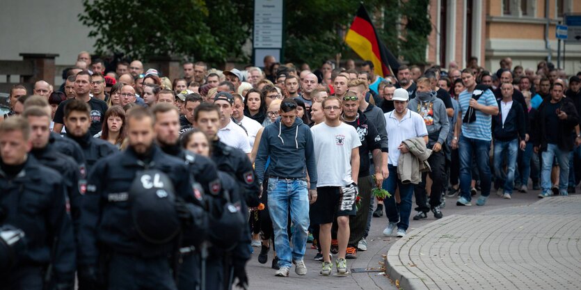 Menschen maschieren hinter Polizisten