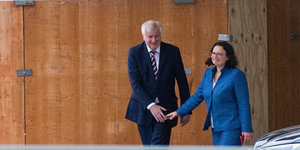 Horst Seehofer und Andrea Nahles gehen Hand in Hand aus einem Gebäude