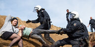 Polizisten ziehen Demonstranten von einem Hügel