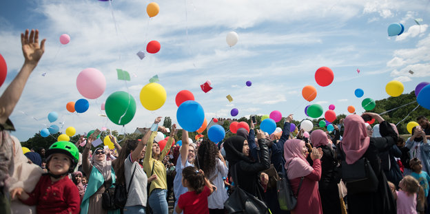 Frauen mit und ohne Kopftuch lassen Luftballons steigen