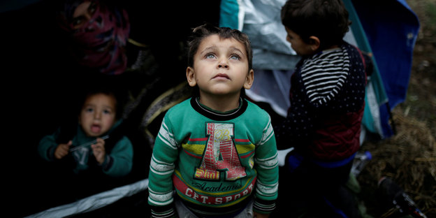 Auf Lesbos steht ein Kind vor einem Zelt während weitere rausgucken