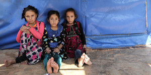 Drei vetriebene syrische Mädchen sitzen vor ihrem Zelt in einem Flüchtlingslager nahe der syrisch-türkischen Grenze in der Provinz Idlib