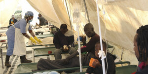 Menschen sitzen in einem Zelt und werden medizinisch behandelt