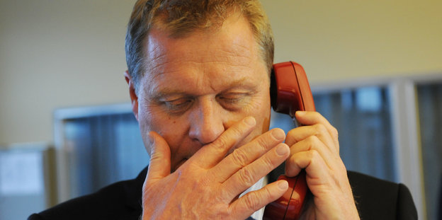Heino Vahldieck am Telefonhörer hält sich eine Hand vor den Mund.