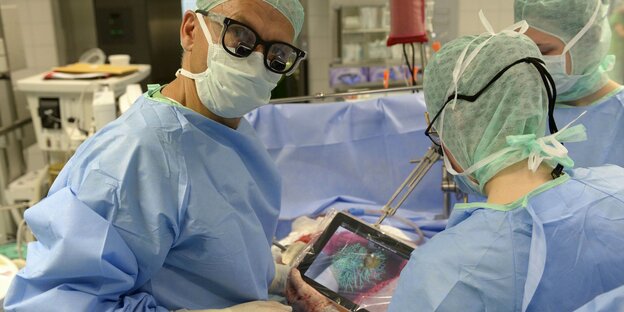 ÄrztInnen benutzen bei einer OP ein Tablet mit einem 3D-Model der Leber
