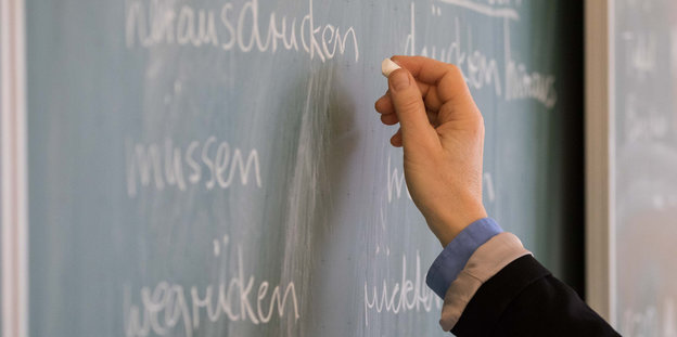 Eine Lehrerin der Oberschule an der Ronzelenstraße steht in einem Klassenraum an einer Tafel und schreibt