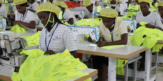 Arbeittende Näherinnen in neonfarbenen Kitteln und Kopftüchern
