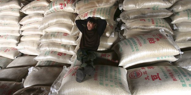 Chinesischer Händler sitzt auf Reissäcken