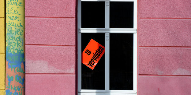 In einem Fenster hängt ein Schild auf dem steht: "Zu vermieten"