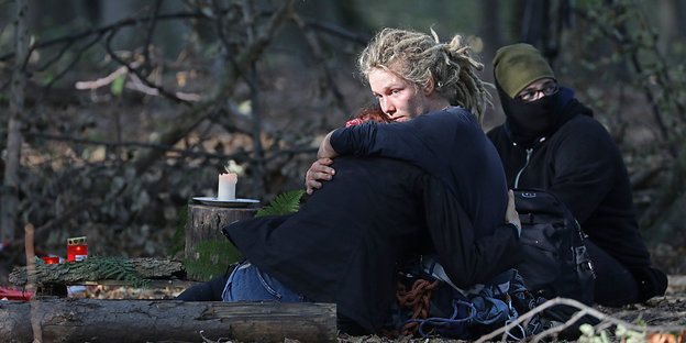 AktivistInnen sitzen auf dem Boden eines Waldes und umarmen sich