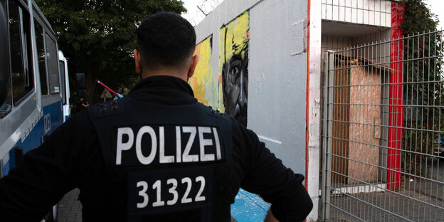 Ein Polizist steht vor dem Wandgemälde, das Nidal R. zeigt