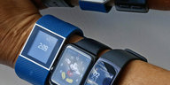 Drei blaue Armbänder mit so genannten Fitness Trackern umschließen einen Arm