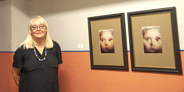 Eine Frau steht neben zwei Bildern an der Wand