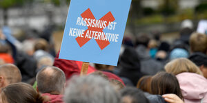 Familienfest des Bündnisses «Rostock Nazifrei» trägt ein Gast ein Schild "Rassismus ist keine Alternative" in AfD-Farben