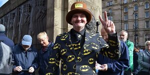 ein Mann in Batman-Sakko macht ein Victory-Zeichen