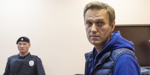 Ein Polizist guckt zu Alexej Nawalny