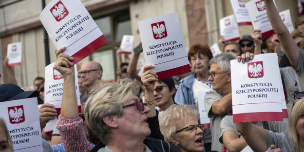 Demonstranten halten Deckblätter der polnischen Verfassung in die Luft