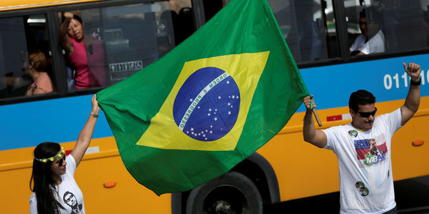 Zwei Wahlhelfer schwenken die brasilianische Flagge