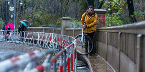 Eine Frau trägt ihr Fahrrad an einer Absperrung entlang