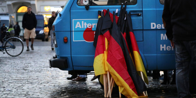 An einem Bus der AfD lehnen Deutschlandfahnen.