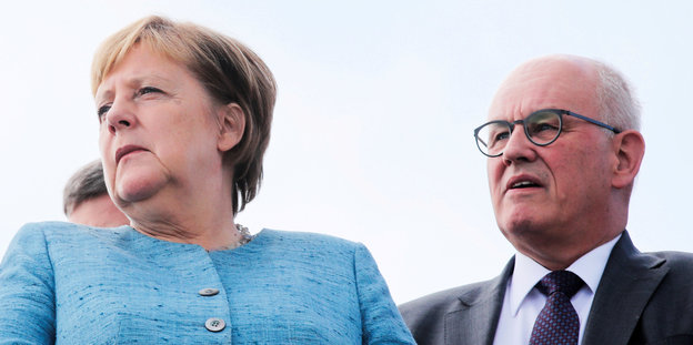 Merkel neben Kaucer, beide gucken schockiert