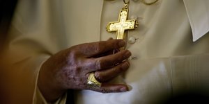 Die Hände des Papstes berühren ein Kruzifix