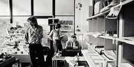 Drei Männer in einem Büro mit vielen Zeitungen