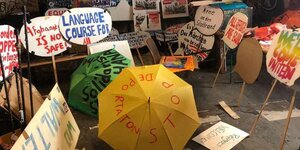Plakate, Schilder und bemalte Regenschirme mit Demo-Slogans.