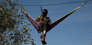 Ein Aktivist hängt an einem Seil zwischen Bäumen im Hambacher Forst