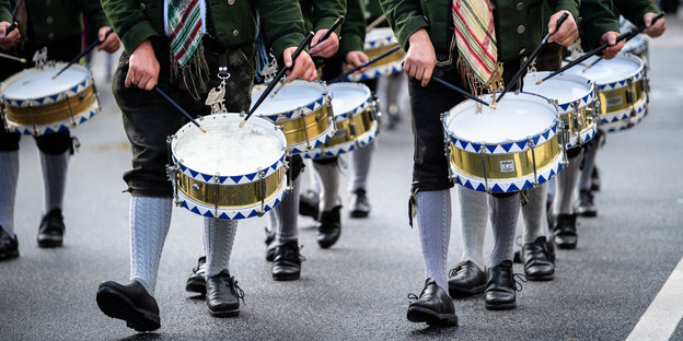 Zu sehen sind die Trommeln und Beine der Trommler einer Musikkapelle, die im Trachten- und Schützenzug zum Münchner Oktoberfest zieht