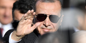 Recep Tayyip Erdoğan mit Sonnebrille in einer Menschenmenge. Er winkt.