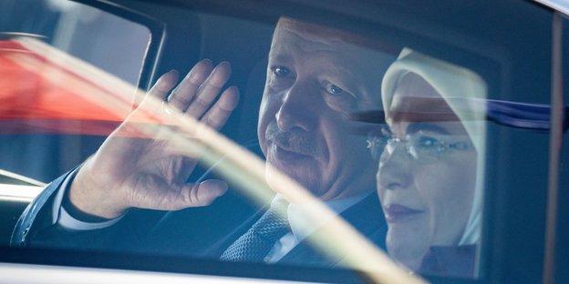 Erdoğan und seine Frau Emine Erdoğan sitzen in einem Auto, er winkt