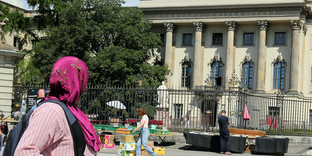 Eine Frau mit Kopftuch geht an der Humboldt-Universität an der Straße Unter den Linden in Berlin vorbe