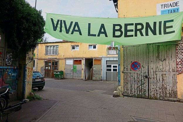 Über einem Hinterhof hängt ein Plakat mit der Aufschrift "Viva La Bernie".