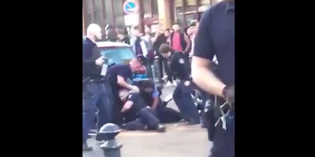 Ein Mann liegt auf dem Boden von Polizisten umringt