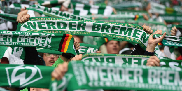 Fans von Werder Bremen halten ihren Schal hoch
