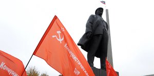 KP-Fahnen unter einem Lenin-Denkmal
