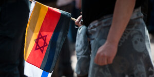 Ein Mann hält eine deutsche und eine israelische Flagge in der Hand