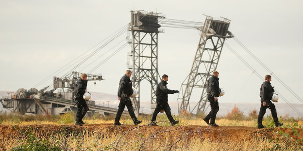 Polizisten vor Kränen des Tagebaus