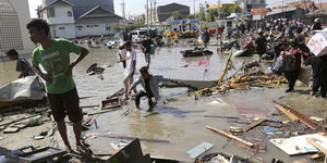 Menschen stehen in Trümmern nach den Erdbeben und dem Tsunami in Palu
