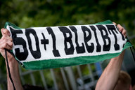 Ein Fan hält ein Banner mit der Aufschrift "50+1 bleibt".