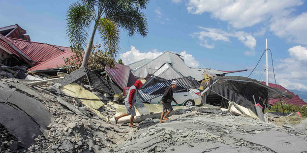 Zwei Menschen laufen über Trümmer in Indonesien